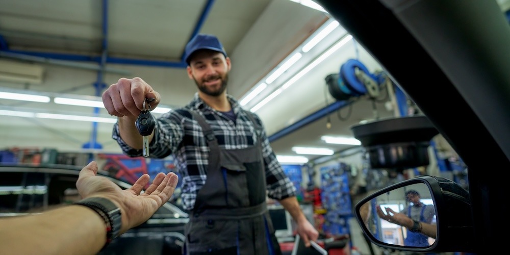 Automotive mechanic handing the keys back to the customer inside their vehicle