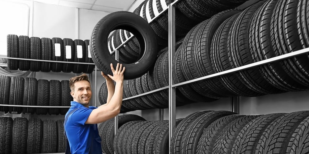 Man taking a tire down from the sales rack